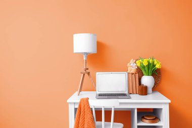 Laptoplu, laleli ve turuncu duvarlı bir iş yeri. Tasarım için pankart