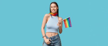Göbek piercingli ve mavi arka planda LGBT bayrağı olan seksi genç kadın.