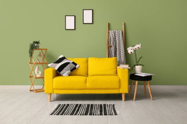 Masalı sarı kanepe, raflar ve yeşil duvarın yanındaki merdiven oturma odasında.