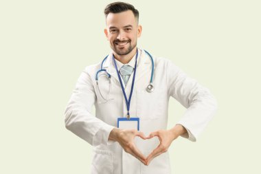 Erkek doktor yeşil arka planda elleriyle kalp yapıyor.