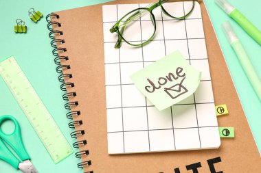 Kelime DONE ile yapışkan not, yeşil arka planda gözlük ve kırtasiye, yakın plan