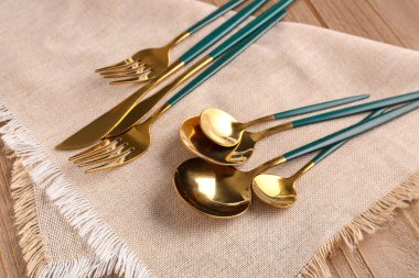 Ahşap arka planda yeşil saplı altın çatal bıçak takımı.