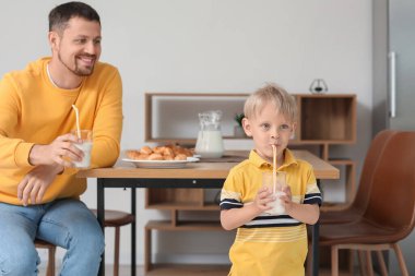 Babasıyla birlikte oturma odasında süt içen küçük bir çocuk.