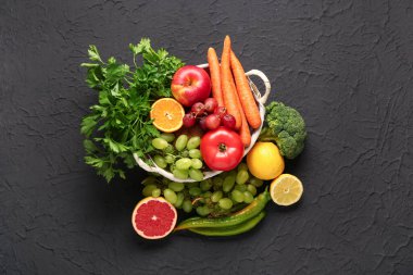 Siyah arka planda farklı taze meyve ve sebzelerle dolu bir sepet.