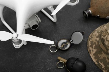 Modern kuadkopter, el bombası, askeri şapka, matara ve siyah arka planda pusula.