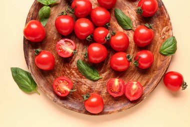 Taze kiraz domatesli ahşap tahta ve turuncu arka planda fesleğen.