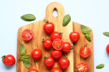 Taze kiraz domatesli ahşap tahta ve mavi arka planda fesleğen.