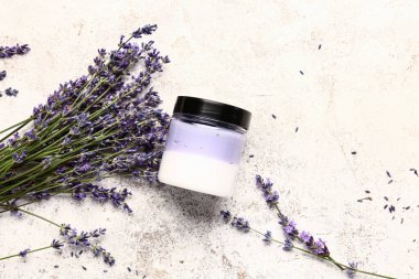 Hafif arkaplanda bir kavanoz kozmetik ürünü ve lavanta çiçeği