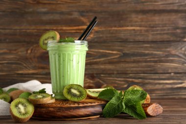 Bir bardak taze kivi suyu ve ahşap zemin üzerinde nane şekeri olan bir tahta.