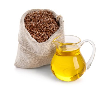 Beyaz arka planda tohumları olan keten yağı ve çuval.