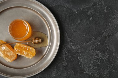 Tatlı bal dolu bir tabak ve koyu arkaplanda taraklar.