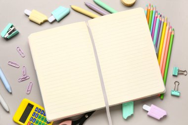 Gri arkaplanda farklı kırtasiye malzemesi bulunan defter