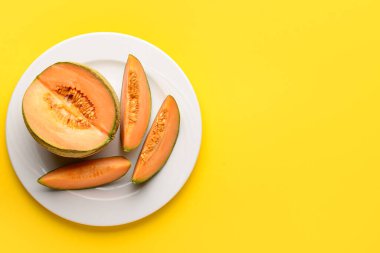 Sarı arka planda lezzetli olgun kavun tabağı.