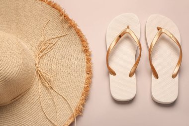 Bej arka planda hasır şapkalı şık kadın terlikleri.