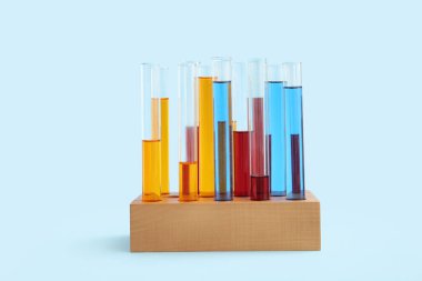 Tahtadan yapılmış renkli numunelerle test tüpleri mavi arka planda duruyor.