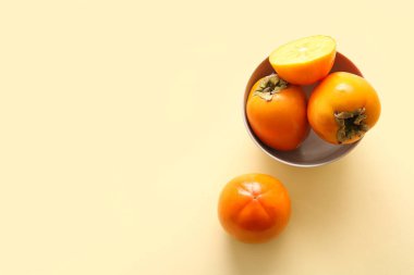 Sarı arka planda tatlı olgun hurmalarla kase