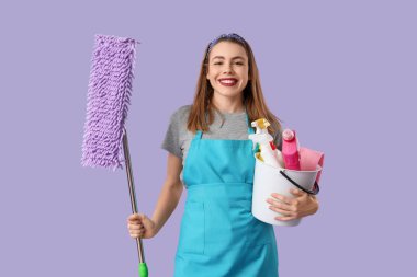 Mor arka planda paspas ve temizlik malzemeleri olan güzel bir kadın.