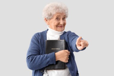 İncil 'i olan yaşlı bir kadın arka plandaki izleyiciyi işaret ediyor. Suçlama kavramı