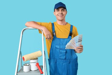 Mavi arka planda renk paletleri ve merdiveni olan genç bir ressam