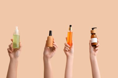 Bej arka planda farklı kozmetik ürünleri tutan kadınlar