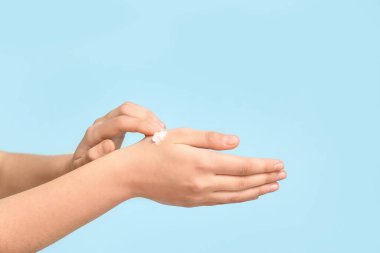 Mavi arka plana kozmetik krem süren kadın