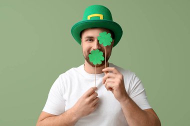 Yeşil arka planda yoncalar olan cüce şapkalı komik genç adam. Aziz Patrick Günü kutlaması