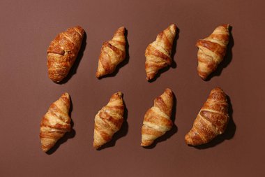 Kahverengi arka planda bir sürü lezzetli kruvasan.