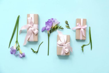 Cyan arka planda doğal çiçeklerle süslenmiş güzel paketlenmiş hediye kutuları.