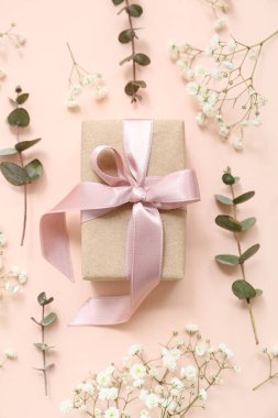 Güzel paketlenmiş hediye kutusu ve bej arka planda çiçekler