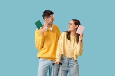 Güzel, genç, mutlu, bavulu ve pasaportu mavi arka planda iki turist.