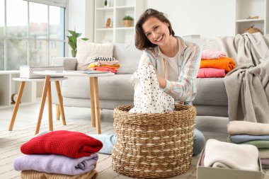 Genç bir kadın evde giysileri katlıyor.