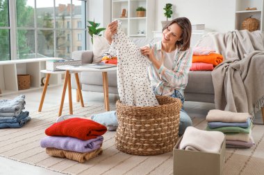 Genç bir kadın evde giysileri katlıyor.