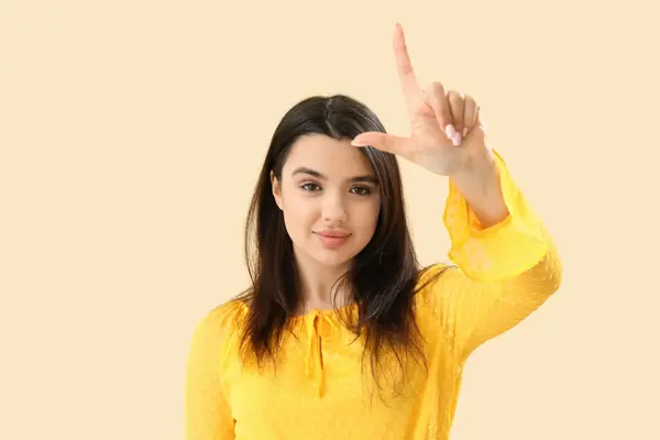 stock image Young woman showing loser gesture on beige background
