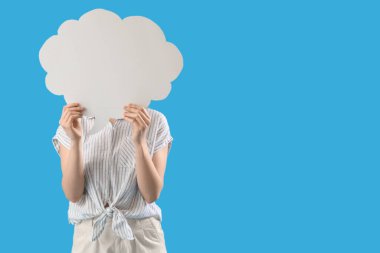 Mavi arka planda boş konuşma balonunun arkasına saklanan genç bir kadın.