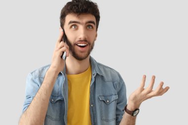 Arka planda cep telefonuyla konuşan yakışıklı genç adam.