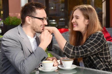 Genç bir adam restoranda sevgilisinin elini öpüyor.
