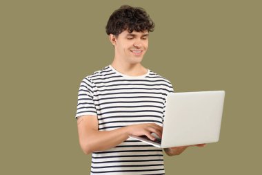 Yeşil arka planda dizüstü bilgisayarla çalışan erkek programcı