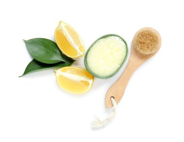Bowl of lemon body scrub with massage brush isolated on white background