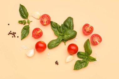 Taze fesleğen, kiraz domatesleri ve turuncu arka planda biber.