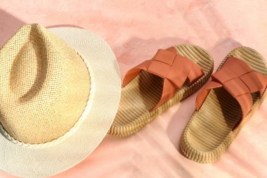 Grunge pembe arka planda hasır şapkalı şık kadın terlikleri.