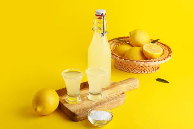 Tahta tahta tahta bir şişe ve sarı arka planda lezzetli limoncello.