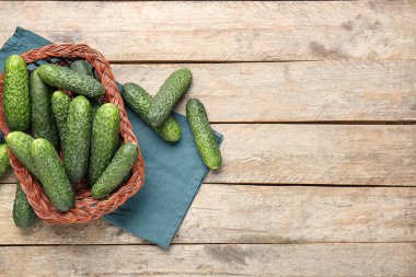 Tahta arka planda taze salatalıklı hasır sepet.