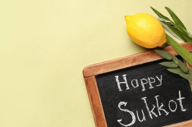 Dört tür (lulav, hadas, arava, etrog) ve yeşil arkaplanda Mutlu SUKKKOT yazılı kara tahta