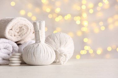 Bulanık ışıklara karşı masasında bitkisel poşetler, havlular ve taşlar bulunan güzel spa kompozisyonu