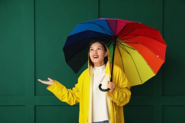 Yeşil arka planda şemsiyesi olan Asyalı güzel bir kadın.