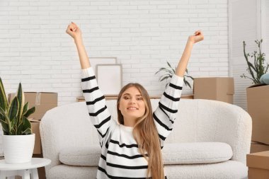 Yeni dairede karton kutularla otururken esnemekten yorgun düşmüş genç bir kadın.