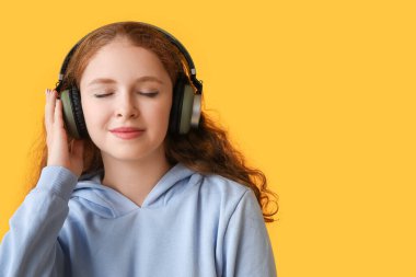 Sarı arka planda müzik dinleyen rahat genç bir kadının portresi.