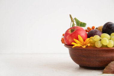 Beyaz arka planda farklı taze meyveler olan bir kase.