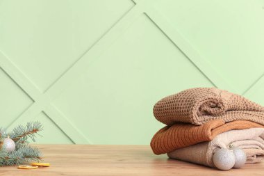 Süveter yığını, köknar ağacı dalı, kurutulmuş limon ve Noel topları ahşap masada.