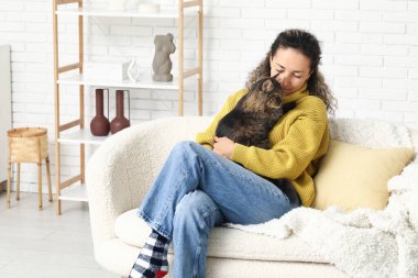 Evdeki kanepede oturan sevimli kedisi olan mutlu olgun bir kadın.
